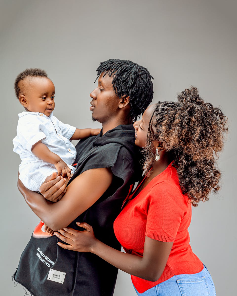 Joyful family moment captured with parents holding their baby in a studio setting.